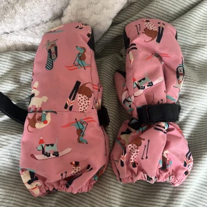Rosa tumvantar med hundmotiv st 122/128 - Säljer ett par rosa tumvantar med gulligt hundmönster i olika färger. Vantarna har svart greppyta i handflatan och justerbart kardborreband vid handleden. Perfekta för kalla dagar och håller händerna varma. Dem är inte tvättade som ni ser på bilden! Detta är för jag inte haft tiden tyvärr. Den är i st 122/128 och i fint skick 💗💗☝🏼