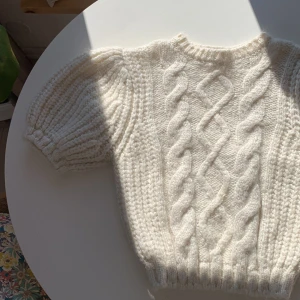 Vit stickad tröja med puffärm från Zara - Superfin vit stickad tröja från Zara med korta puffärmar och grovt flätmönster framtill. Tröjan är mjuk och har ribbade muddar vid ärmslut och nederkant. Jätte mysigt lyxigt material, i alpacka ull blend. Köpte vintage i Stocholm, men aldrig använt. Passar mig som är XS-S