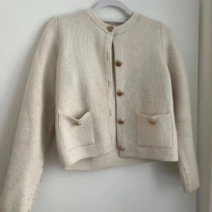 Beige stickad cardigan jacka från Zara - Säljer en beige stickad cardigan jacka från Zara med guldfärgade knappar och två fickor framtill. 
