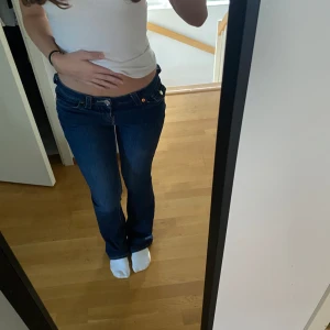 Mörkblå jeans från True Religion - Säljer ett par mörkblå jeans från True Religion med klassiska kontrastsömmar och snygga fickdetaljer med logga bak. Jeansen har låg midja och bootcut passform, perfekta till vardagslooken.