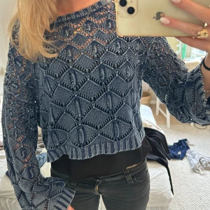 Blå stickad croppad tröja från Zara - Säljer en blå stickad croppad tröja från Zara med genombrutet mönster och långa ärmar. Tröjan har en avslappnad passform och är perfekt att styla över ett linne eller topp.