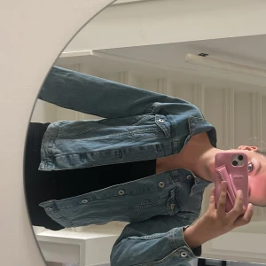 Ljusblå jeansjacka  - Säljer en klassisk ljusblå jeansjacka från 157 med silverfärgade knappar framtill och två bröstfickor med lock. Jackan har en rak passform och är långärmad. Den är i storlek 160 men passar även mig som har 170 och xs 