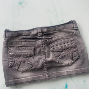 Grå jeanskjol med stjärndetaljer från House Denim - Säljer denna korta jeanskjol från House Denim i storlek XS🌸Midjemåttet rakt över är ca 38cm och längden är ca 27cm 