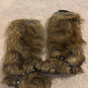 Bruna pälsboots från Miu Miu - Unika boots från Miu Miu med lång, brun pälsimitation och grov sula med stjärnmönster. Skorna har dekorativa nitar och en robust känsla, perfekta för dig som vill sticka ut med din stil.