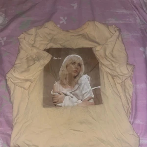 Beige t-shirt med tryck - Ljusgul/beige tshirt från billie eilish, säljs ej längre. Från hennes album Happier Than Ever. Den passar 13-16 åringar. Den är inte stryken därför ser den ut så på bild men när den köps stryker jag den