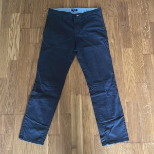 Mörkblå chinos från Gant - Snygga mörkblå chinos från Gant med klassisk rak passform. Byxorna har framfickor, bakfickor med knapp och stängs med knapp och dragkedja. Perfekta för en stilren look.