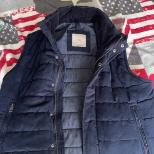 Mörkblå quiltad mocka väst från Mango - Stilren mörkblå mocka väst från Mango med quiltat mönster och dragkedja framtill. Den är så gott som ny, Västen har två fickor med dragkedja och hög krage. Perfekt för lager-på-lager och passar till många olika outfits. Priset är såklart förhandlingsbart👑🔥