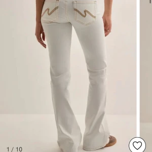 Vita bootcut jeansbyxor från Nelly  - Säljer de populära vita bootcut jeansen från nelly med klassiska bakfickor och kontrastsömmar. Byxorna har låg midja och utsvängda ben, perfekt för en trendig look. Stängs med dragkedja och dubbla knappar framtill. De är aldrig använda och därför i nyskick, säljer pågrund av att de är för långa för mig :( 💕💕