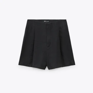 Svarta tygshorts från Zara - Stilrena svarta shorts från Zara med hög midja och raka ben. Klassisk design utan synliga detaljer, perfekta för en clean look. Tillverkade i ett mjukt material som ger en dressad känsla. OANVÄND, PRISLAPPEN SITTER KVAR!
