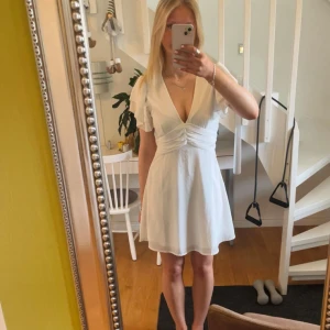 Vit klänning med volangärmar - Superfin vit klänning med v-ringning och korta volangärmar. Perfekt för studenten eller examen💞. 