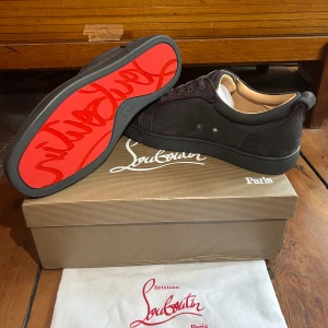 Skor från Christian Louboutin - Snygga grå sneakers i mocka från Christian Louboutin med den ikoniska röda sulan. Skorna har snörning och en stilren design som passar perfekt för en trendig look. Skriv priv om frågor eller annat!