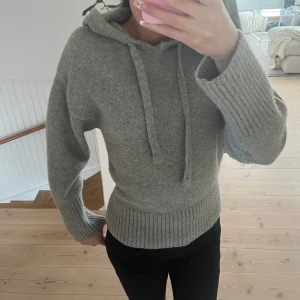 Grå stickad hoodie från Zara - Säljer en mysig grå hoodie från Zara. Den har en bekväm passform med långa ärmar och en stor huva med dragsko. Perfekt för kyliga dagar. Ribbstickade muddar och nederkant ger en snygg detalj.🥰säljer pågrund av att den inte kommer till användning!!💕