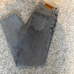 Grå jeans från Woodbird - Snygga grå jeans från Woodbird med klassisk femficksdesign och knappgylf. I mycket fint skick. De har en rak passform och är perfekta för en avslappnad stil. Tillverkade i slitstarkt denim som ger en cool look. Hör av er vid frågor!
