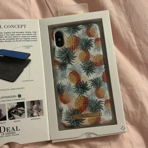 Pineapple Bonanza mobilskal från iDeal of Sweden - Snyggt mobilskal med ananasmönster från iDeal of Sweden, designat för iPhone XS Max. Skalet har en tropisk känsla med färgglada ananaser mot en vit bakgrund. Perfekt för att ge din telefon en unik och somrig look.