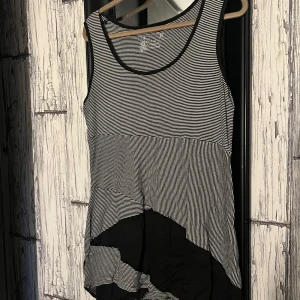 Randig ärmlös klänning från Desigual - Snygg ärmlös klänning från Desigual med svartvitt randigt mönster och asymmetrisk design. Perfekt för en avslappnad stil med en twist. Klänningen har en unik kombination av ränder och blockfärger som ger en cool look.