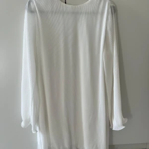 Vit långärmad klänning  - Säljer en stilren vit klänning med långa ärmar och diskret ribbad struktur. Perfekt för en elegant och minimalistisk look.
