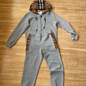 Burberry Tracksuit  - Säljer en snygg grå hoodie med matchande byxor från Burberry. Perfekt för en stilren och bekväm look. Helt nya, aldrig använda! Storlek S på byxor samt tröja. Säljs då de ej passade min stil. Hör av er för mer info/bilder! Pris kan diskuteras vid snabbt köp!