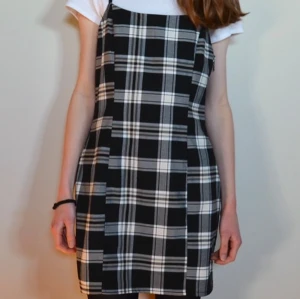 Svart och vit rutig klänning - Snygg svart och vit rutig klänning med smala axelband. Klänningen har en tight passform och är knälång. Säljer för att den är för stor för mig, klänningen är storlek 40. Använd endast 2-3 gånger, inga defekter! 