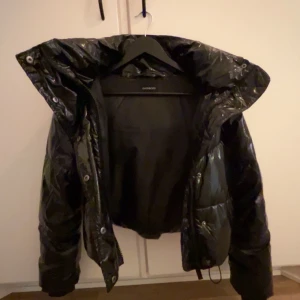 Svart glansig dunjacka från zalando - Säljer min fina jacka för den inte riktigt är min stil längre andvänd ett par gånger bara men den är väldigt varm och härlig.