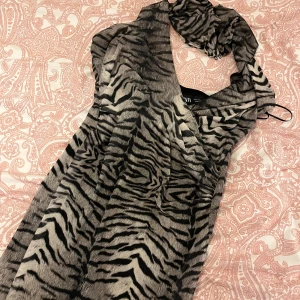 Zebramönstrad klänning från Zara - Snygg zebramönstrad klänning från Zara med omlott-design. Klänningen har en stilren look och är perfekt för att sticka ut. Den är gjord i ett mjukt material som känns skönt mot huden. (Aldrig använd)
