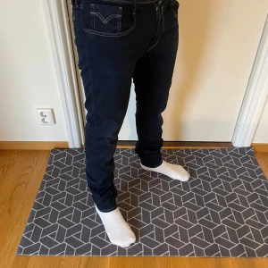 Replay Anbass Hyperflex - Snygga mörkblå jeans från Replay i modellen Anbass. De har en klassisk design med vita sömmar och en bekväm passform. Perfekta för en stilren look.                           Storlek: W34 L36