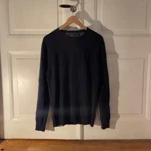 Mörkblå tröja från Ralph Lauren - Säljer en stilren mörkblå tröja från Ralph Lauren. Tröjan har en klassisk design med rund hals och långa ärmar. Perfekt för en elegant och avslappnad look. 
