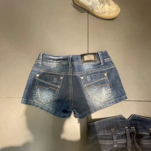 Blå jeansshorts från Replay - Snygga blå jeansshorts från Replay med klassisk femficksdesign och slitna detaljer. Perfekta för en avslappnad stil. De har en knapp och dragkedja framtill.