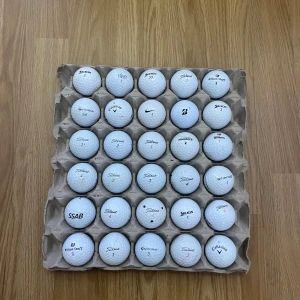 Samling av golfbollar från olika märken - En samling av golfbollar från olika märken som Titleist, Nike, Callaway och Bridgestone. Perfekt för golfentusiaster som vill ha en variation av bollar att spela med. Bollarna är placerade i en kartonghållare för enkel förvaring och transport. Pris är som alltid förhandlingsbart!