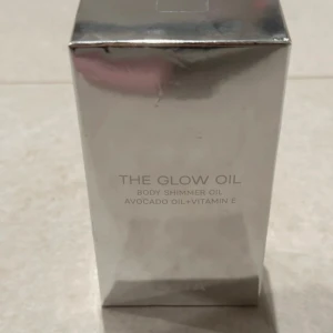 The Glow Oil Body Shimmer Oil - The Glow Oil är en kroppsolja med skimmer som innehåller avokadoolja och vitamin E. Perfekt för att ge huden en strålande glans och återfuktning.