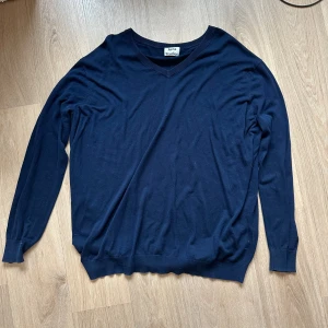 Mörkblå tröja från Acne Studios - Säljer en stilren mörkblå tröja från Acne Studios. Tröjan har en v-ringad hals och långa ärmar, perfekt för en avslappnad men snygg look. Passar bra till både jeans och chinos. Perfekt för kyligare dagar!