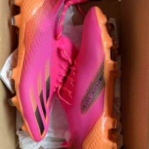 Rosa fotbollsskor från Adidas - Snygga rosa fotbollsskor från Adidas med orange sula och svarta detaljer. Skorna är i storlek 40 2/3. Passar för mig som vanligtvis har 40 i fotbollsskor.