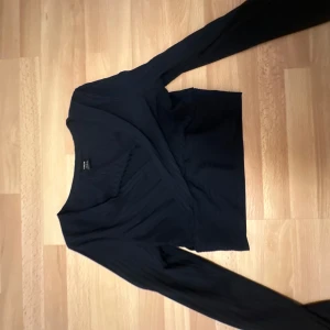 Vit omlottopp - Säljer en stilren vit och svart omlottopp med långa ärmar. Perfekt för en elegant look.