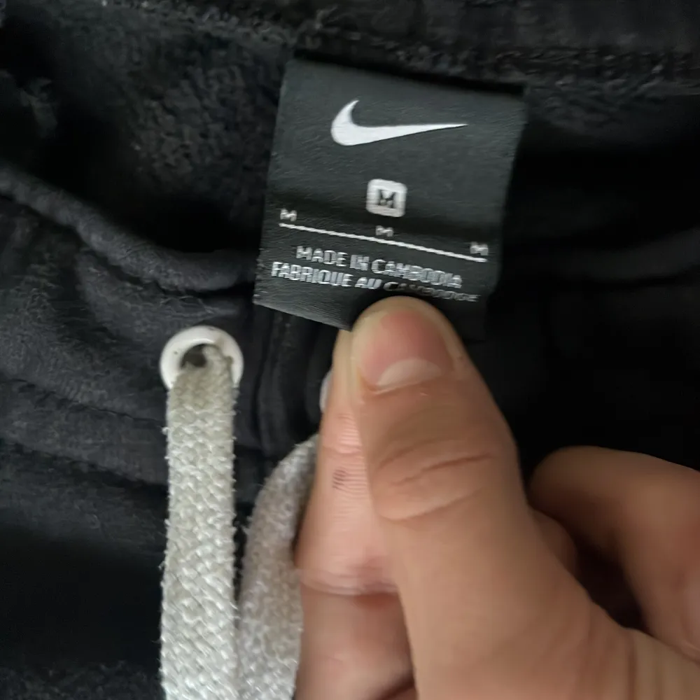 Säljer ett par svarta mjukisbyxor från Nike med vit dragsko i midjan och den klassiska Nike-loggan på benet. Byxorna har en bekväm passform och är perfekta för avslappnade dagar.. Farkut & Housut.