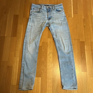 Ljusblå jeans från Nudie Jeans - Säljer ett par ljusblå jeans från Nudie Jeans, i den populära modellen Lean Dean💯. De har en klassisk femficksdesign med dragkedja och knapp. Jeansen är tillverkade i en bomullsblandning med en liten del elastan för extra komfort. Använda lite och sparsamt så det är i väldigt bra kondition utan några tecken på användning👍Perfekta för en avslappnad stil. ✅Skriv till mig vid frågor så svarar jag snabbt😊