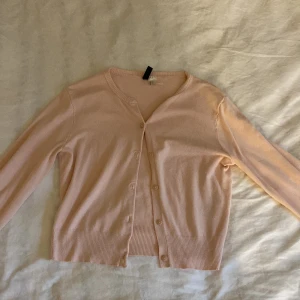 Ljusrosa kofta från Divided - Säljer en söt ljusrosa kofta från Divided. Den har långa ärmar och knappar framtill. Perfekt för att lägga till en mjuk touch till din outfit. Passar bra till både jeans och kjol. 💖