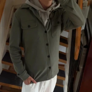 Grön overshirt från Only & Sons - Säljer en stilren grön overshirt från Only & Sons. Jackan har långa ärmar och knappar framtill samt två bröstfickor med lock. Perfekt för lager-på-lager-stil och passar bra till både hoodie och t-shirt.