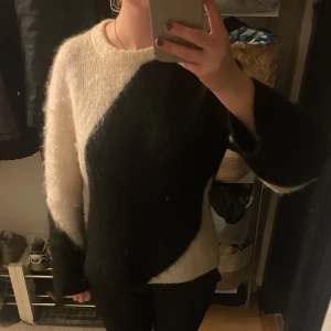 Svart och vit stickad tröja - Säljer en mysig stickad tröja i svart och vitt med ett unikt diagonalt mönster. Använd sparsamt men kan lukta lite parfym, nypris 1200