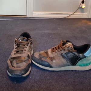 Valentino rockrunners  - Snygga Valentino sneakers med ett coolt camouflage mönster. Skorna har snörning och detaljer i blått och grönt. Perfekta för dig som vill ha en unik stil. Kan gå ner i pris vid snabb affär.