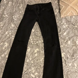 Svarta jeansbyxor - Snygga svarta jeansbyxor med klassisk design. De är utsvängda. Ganska slitna plus hål vid knäna 