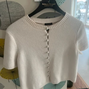 Vit kortärmad kofta från Massimo Dutti - Säljer en stilren vit kofta från Massimo Dutti med korta ärmar och knappar framtill. Använd endast en gång! Storlek S