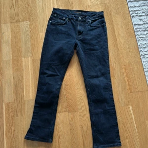 Mörkblåa jeans från Nudie Jeans - Snygga mörkblåa jeans från Nudie Jeans. De har en rak passform och är tillverkade i ett slitstarkt denimtyg, men detaljer på bakfickorna. Perfekta för en stilren look. Storlek W32, L34. 