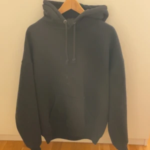 Svart hoodie från Bik Bok - Säljer en svart hoodie från Bik Bok i storlek M. Den har en klassisk design med en stor ficka framtill och justerbar huva med dragsko. Perfekt för en avslappnad stil.