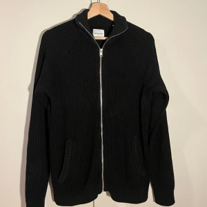 Svart ribbad cardigan Jack&Jones - Snygg svart ribbad kofta från Jack&Jones med dragkedja framtill. Passar både till vardags och med skjorta under till mer uppklädda tillfällen. Skick 7/10. Storlek M. Mitt pris: 110 kr, Nypris: 599.