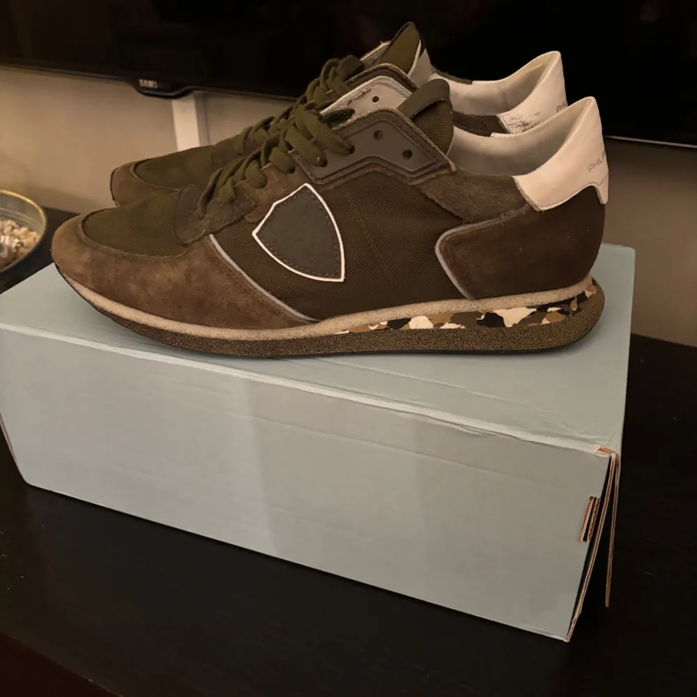 Snygga gröna trainers från Philippe Model med en kombination av mocka och syntetmaterial i storleken 42. Skorna har en unik kamouflagemönstrad sula och snörning framtill. Perfekta för en stilren och avslappnad look. Köpt från Vestiaire för 2500 och använda ett par gånger men bra kvalitet. . Kengät.