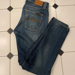 Blåa Nudie jeans  - Snygga blå jeans från Nudie Jeans med orange sömmar. Jeansen har en slim passform och är tillverkade i slitstarkt denim. Perfekta för en avslappnad stil. Om du har några frågor är det bara att skriva in!💯