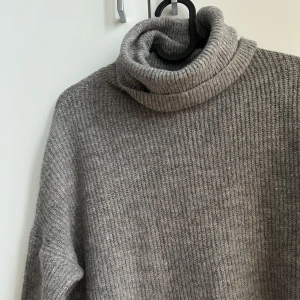 Stickad polotröja - Stickad polotröja med en hög krage och slits på sidorna från New Yorker.