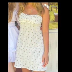 Blommig vit klänning - Charmig vit klänning med blommigt mönster. Den har en smickrande passform och är ärmlös, perfekt nu inför sommaren, endast använd en gång på midsommar!! 🎀💘💞 