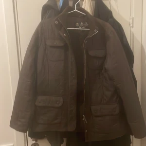 Brun quiltad jacka från Barbour - Säljer en snygg brun quiltad jacka från Barbour. Jackan har långa ärmar och praktiska fickor med knappar framtill. Perfekt för kyligare dagar med sin stilrena design och funktionella detaljer. Fler bilder kan tas om det önskas, skulle säga att den passar M kanske lite mindre L