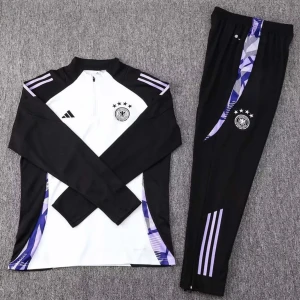 Tyskland tracksuit - Snygg fotbollströja och byxor från Adidas i svart och vitt med lila detaljer. Tröjan har långa ärmar och en halv dragkedja framtill. Byxorna har tre lila ränder längs sidan. Perfekt för träning eller avslappnad stil.