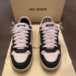 Svartvita sneakers från Axel Arigato - Snygga svartvita sneakers från Axel Arigato med klassisk snörning. Påse och låda ingår. Nypris: 2549kr. Storlek: 44. 